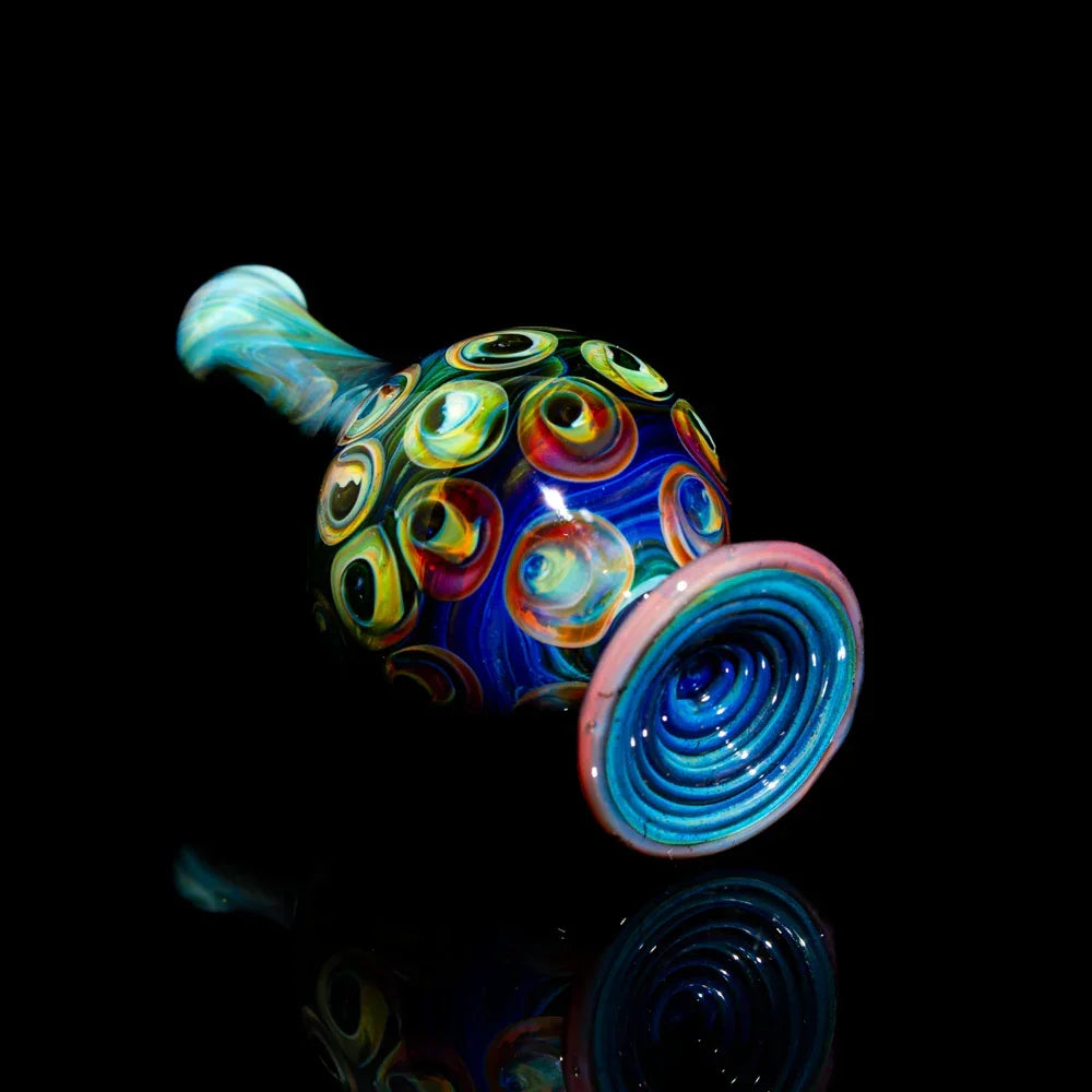 Colorful heady glass hand pipe with swirling patterns and eye-inspired designs on black background