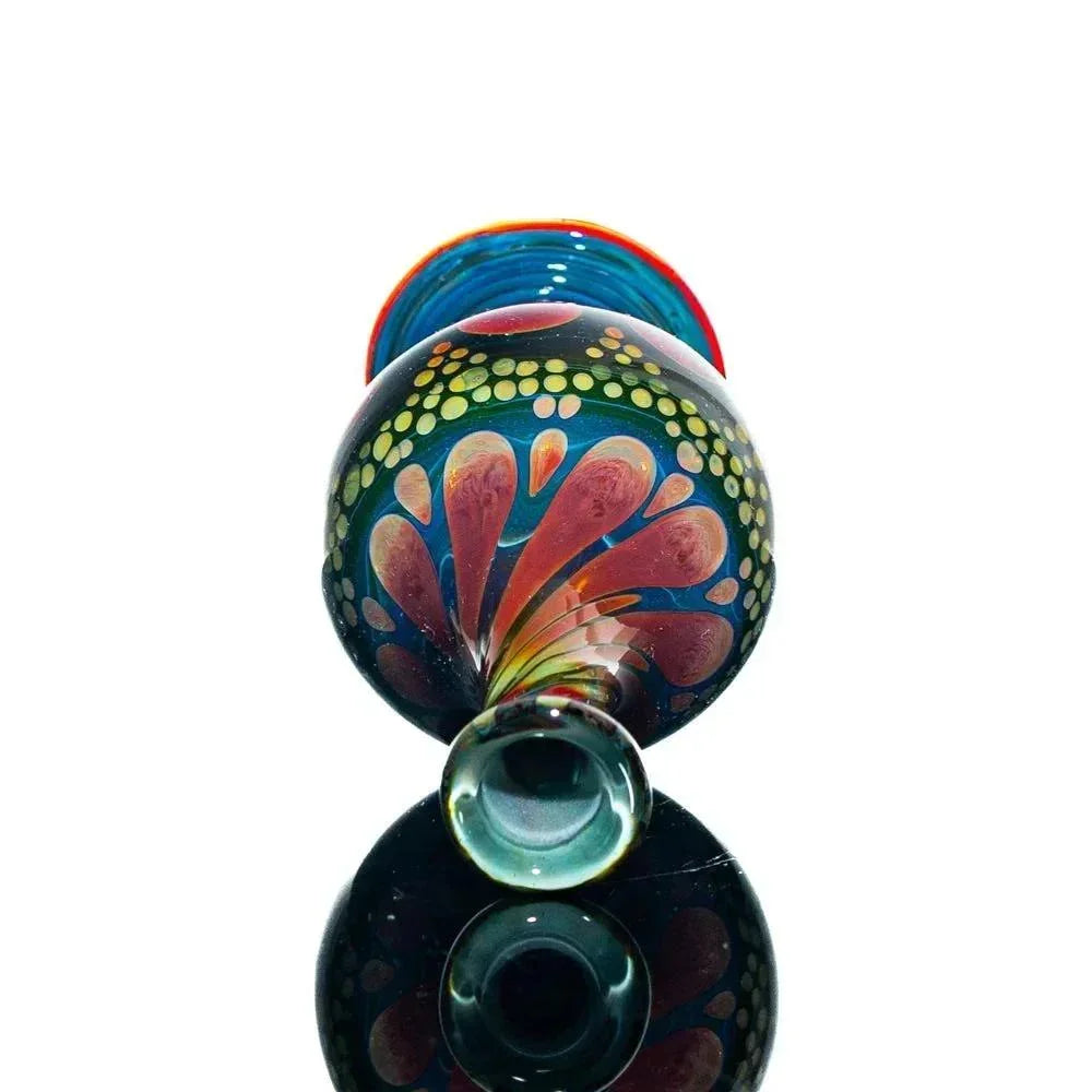 Colorful hand-blown glass jar with vibrant floral pattern, reflected on black surface.