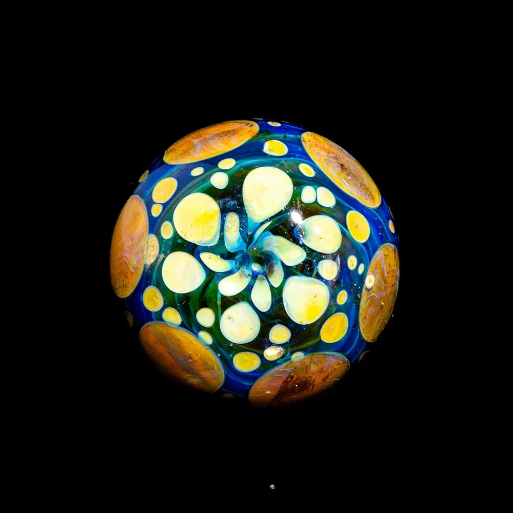 Colorful heady glass marble with intricate yellow, orange, and blue dot pattern on black background