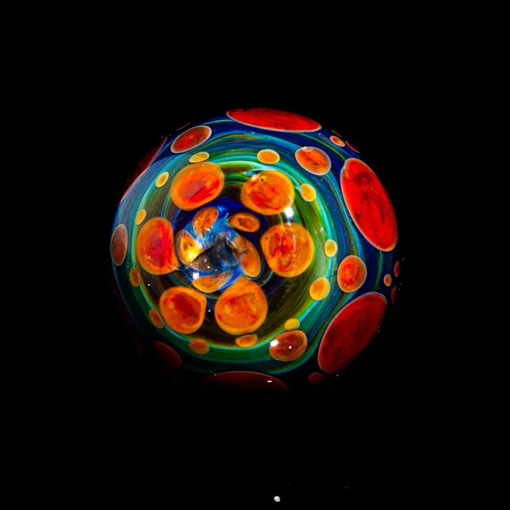 Colorful glass marble with vibrant orange dots and swirling blue and green patterns on black background