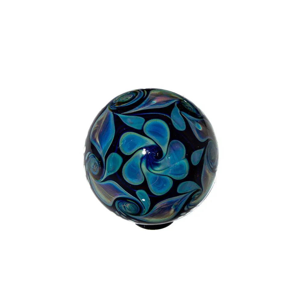 Handcrafted glass marble with blue and green swirled pattern on white background