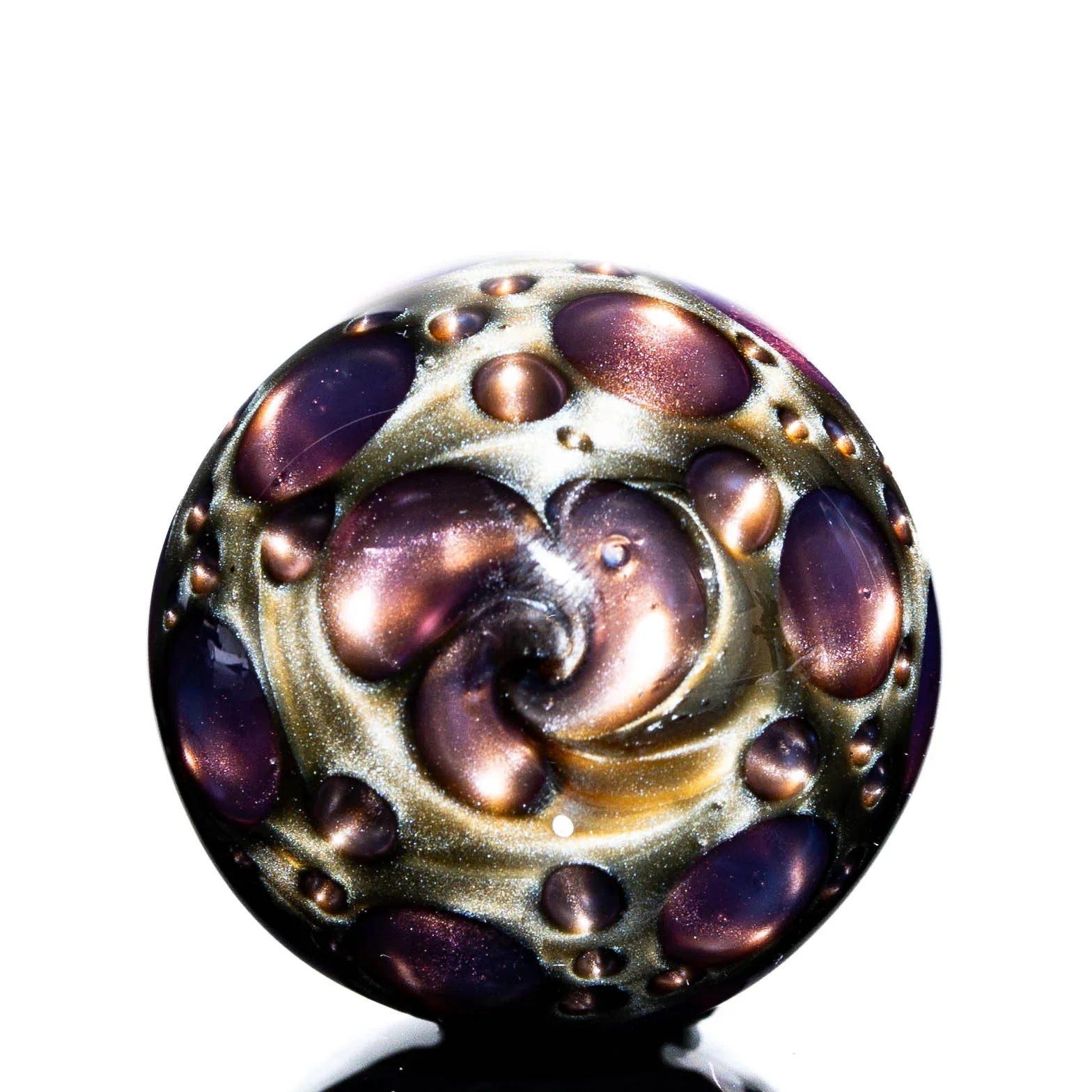 Hand-blown glass marble with purple and gold swirl patterns and raised bubble accents