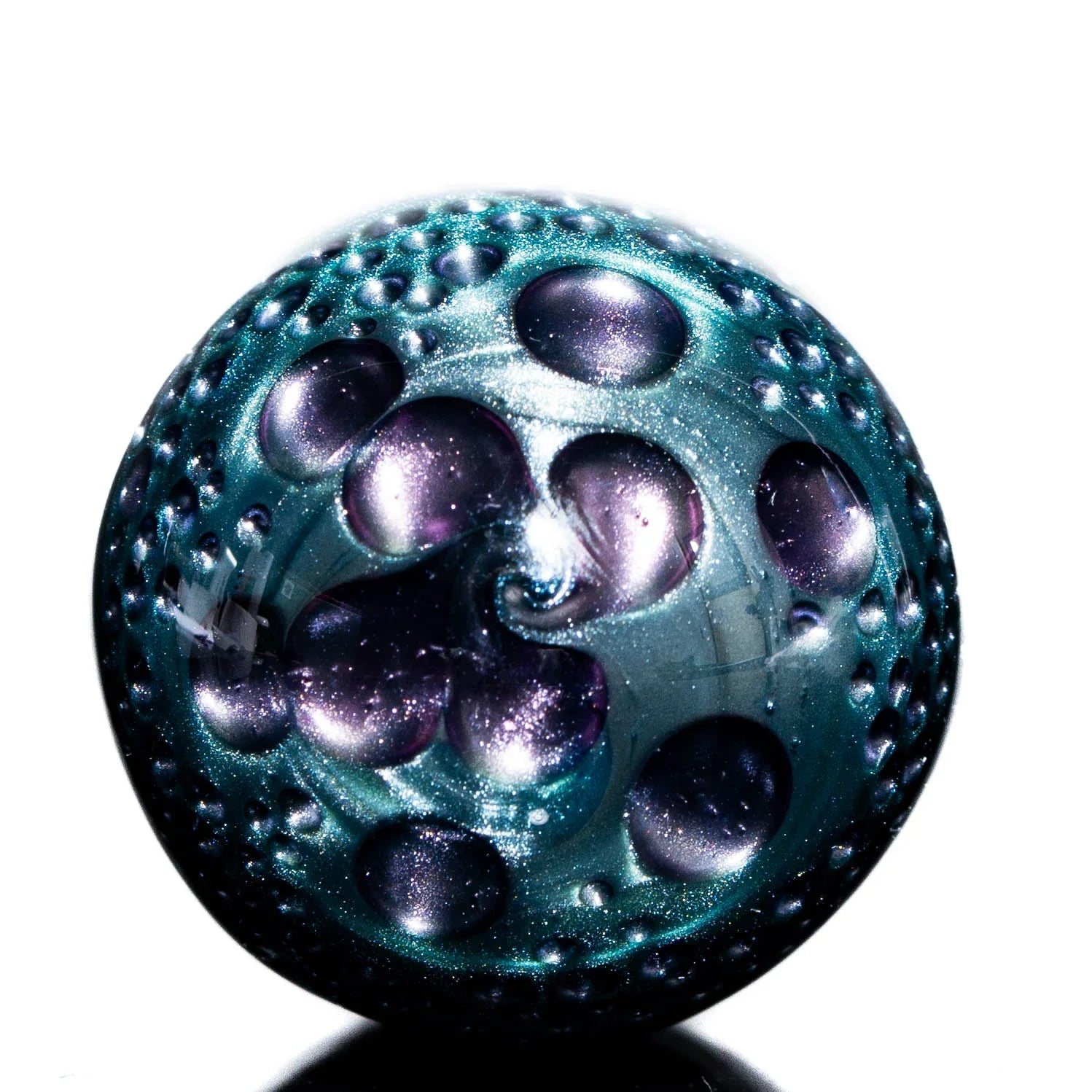 Iridescent purple and teal glass marble with textured, bubble-like patterns on a white background.