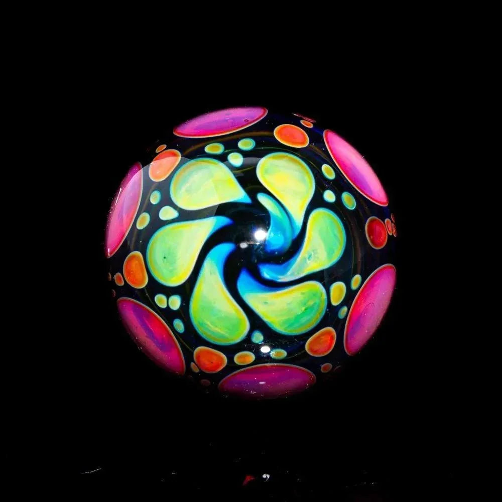 Hand-blown glass marble with vibrant pink, yellow, and green swirl pattern on black background