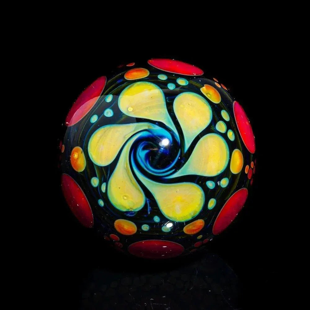 Handcrafted glass marble with vibrant swirl and hobnail dot pattern on black background