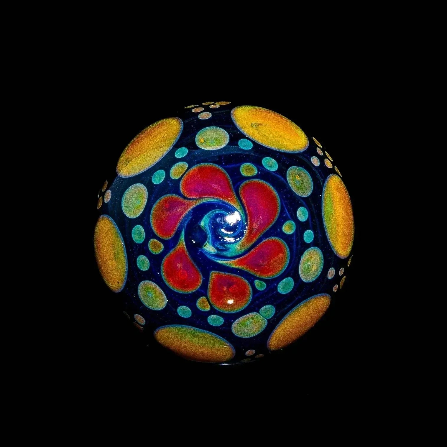 Heady glass marble with vibrant blue, green, red, and yellow coral-inspired design on black