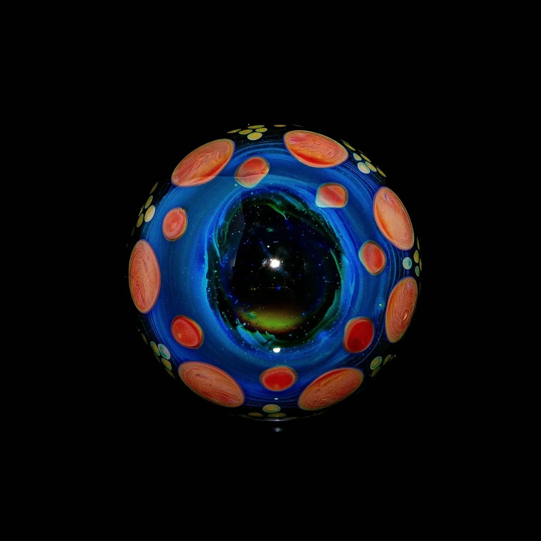 Blue and red hobnail glass marble with yellow accents on a black background