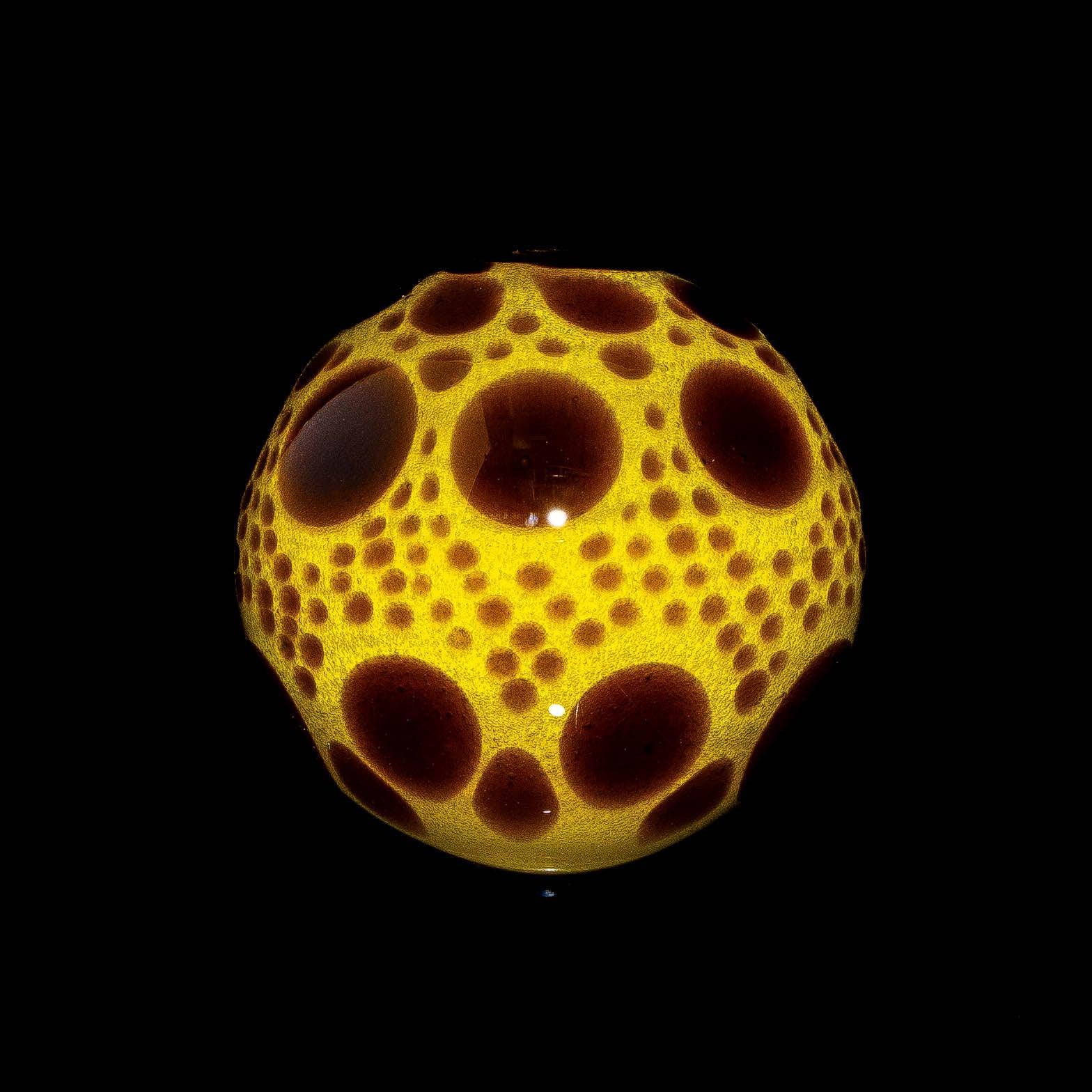 Yellow sable hobnail glass sphere with raised brown dot accents on black background