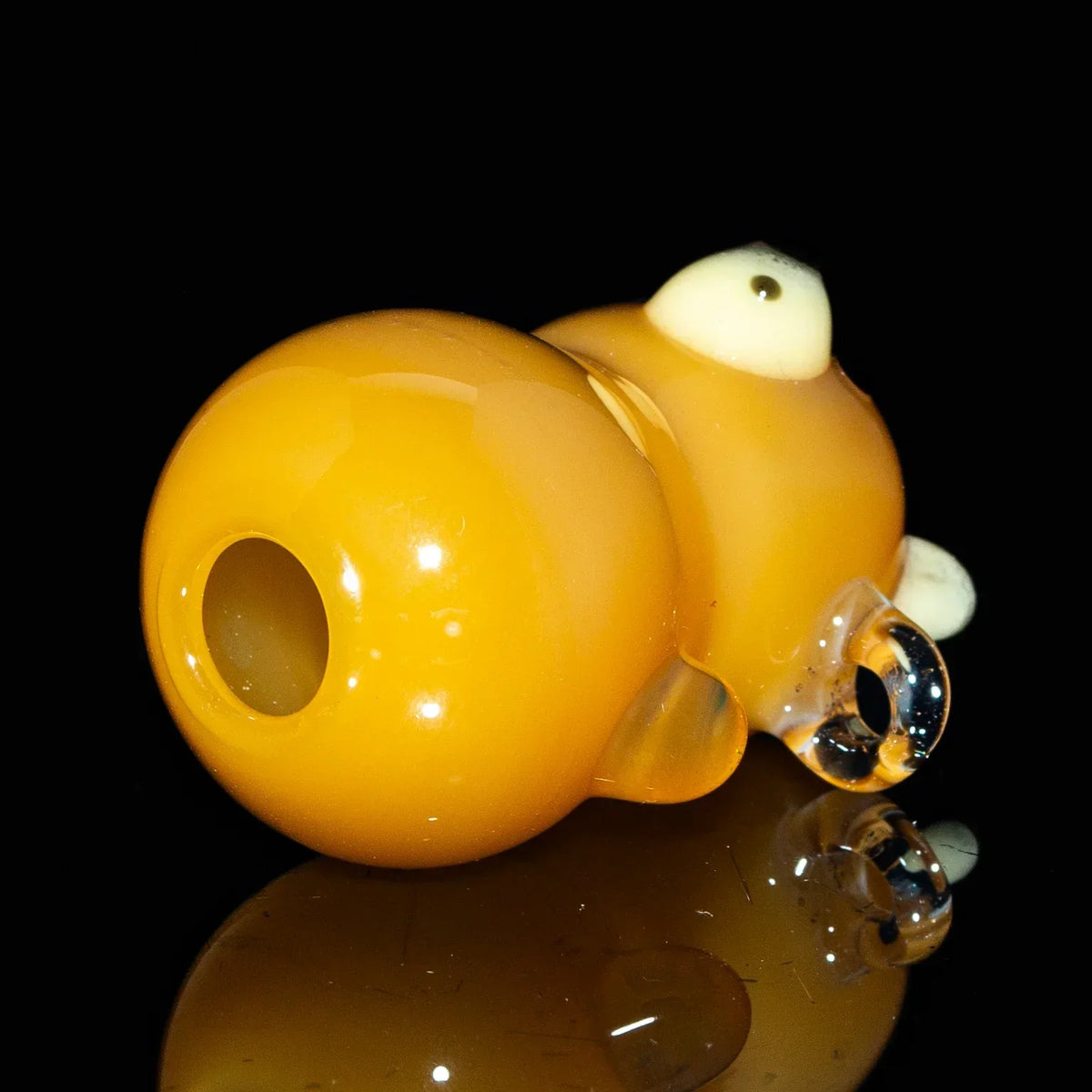 Brown glass bear-shaped joint holder accessory on a black reflective surface