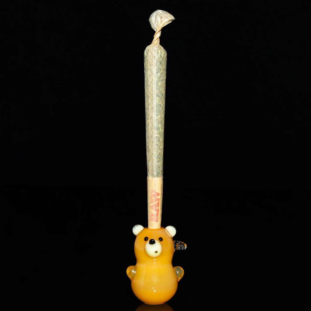 Glass bear joint holder with pre-roll, novelty smoking accessory against black background