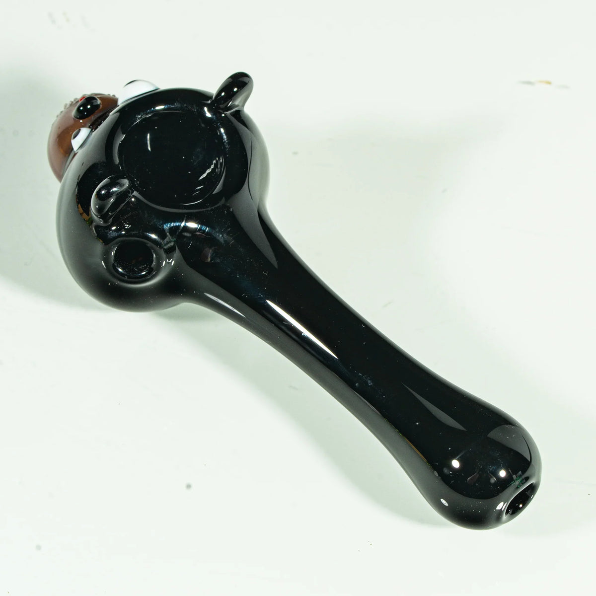 Black glass hand pipe shaped like a bear, featuring detailed bear face and rounded bowl