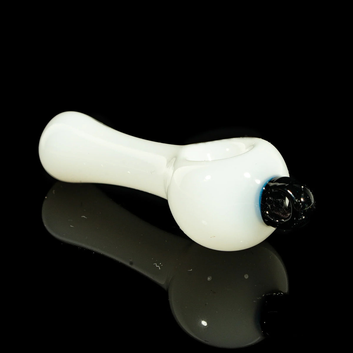 White glass spoon pipe with galaxy accent on black reflective surface