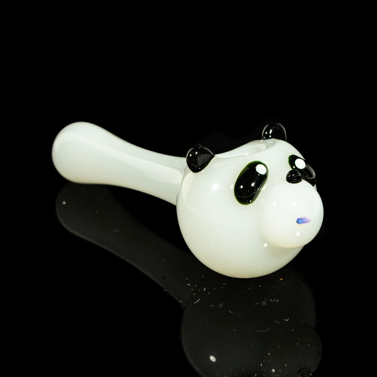 Glass hand pipe shaped like a panda bear with black ears and eyes on a black background.