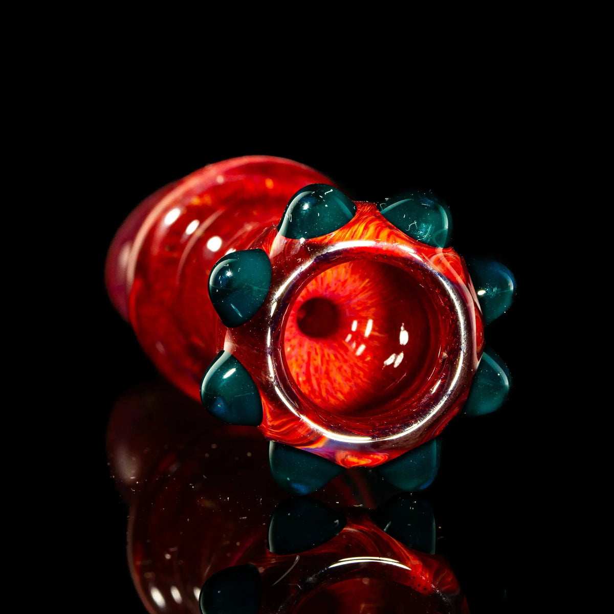 Red frit glass pipe with teal marble accents on black reflective surface