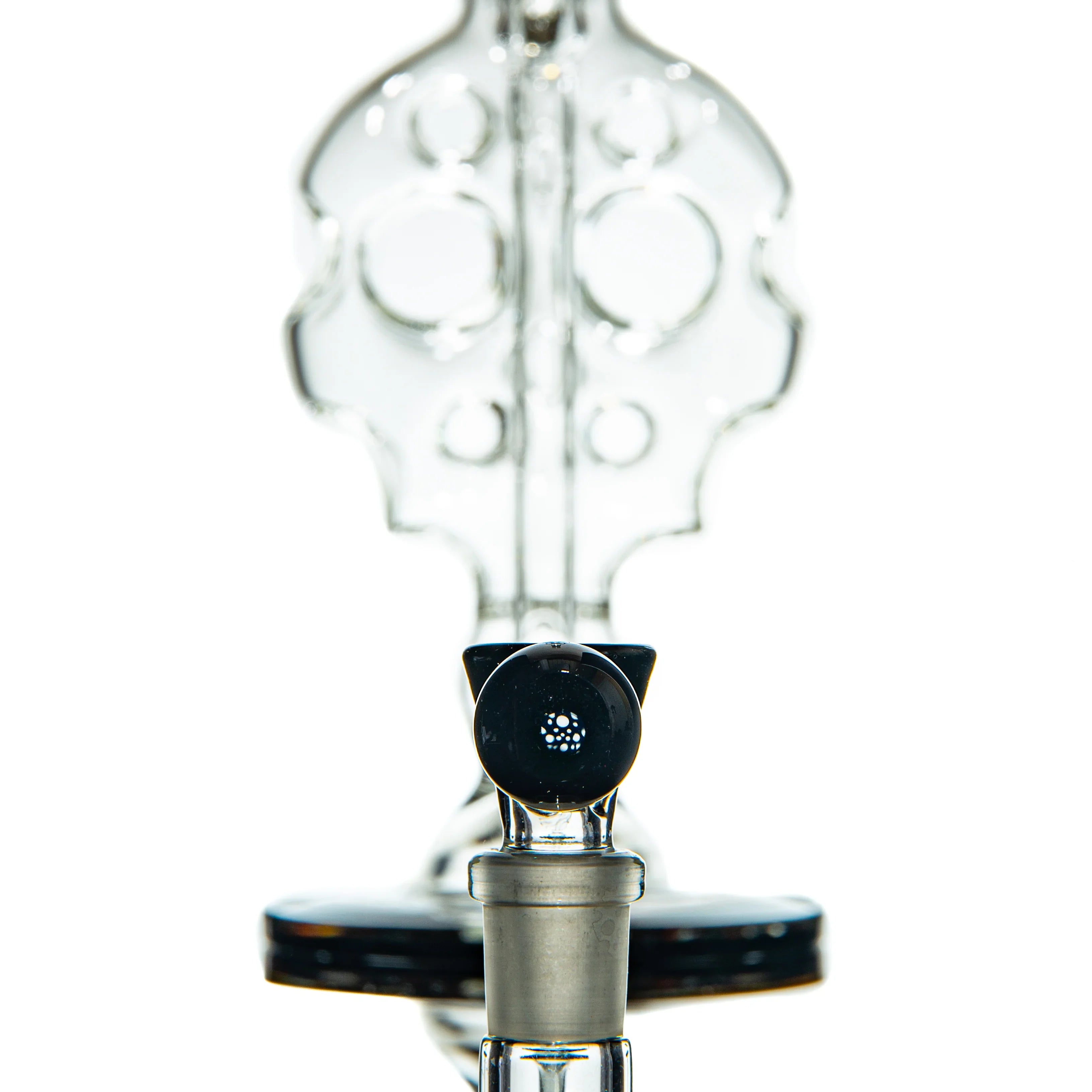 Close-up of intricate clear glass water pipe with unique percolator design, studio background