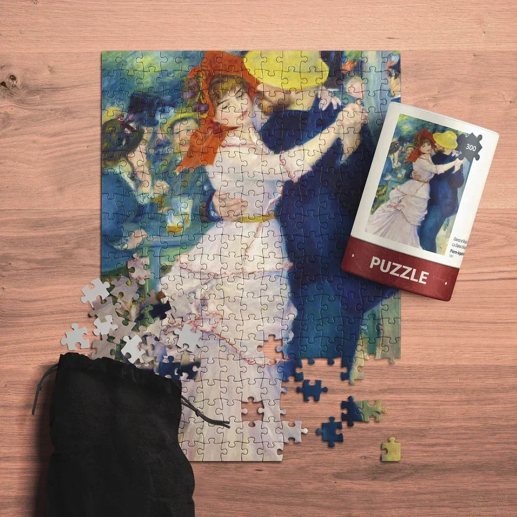 Partially completed art puzzle with dancing couple, loose pieces, and puzzle tube on wooden table