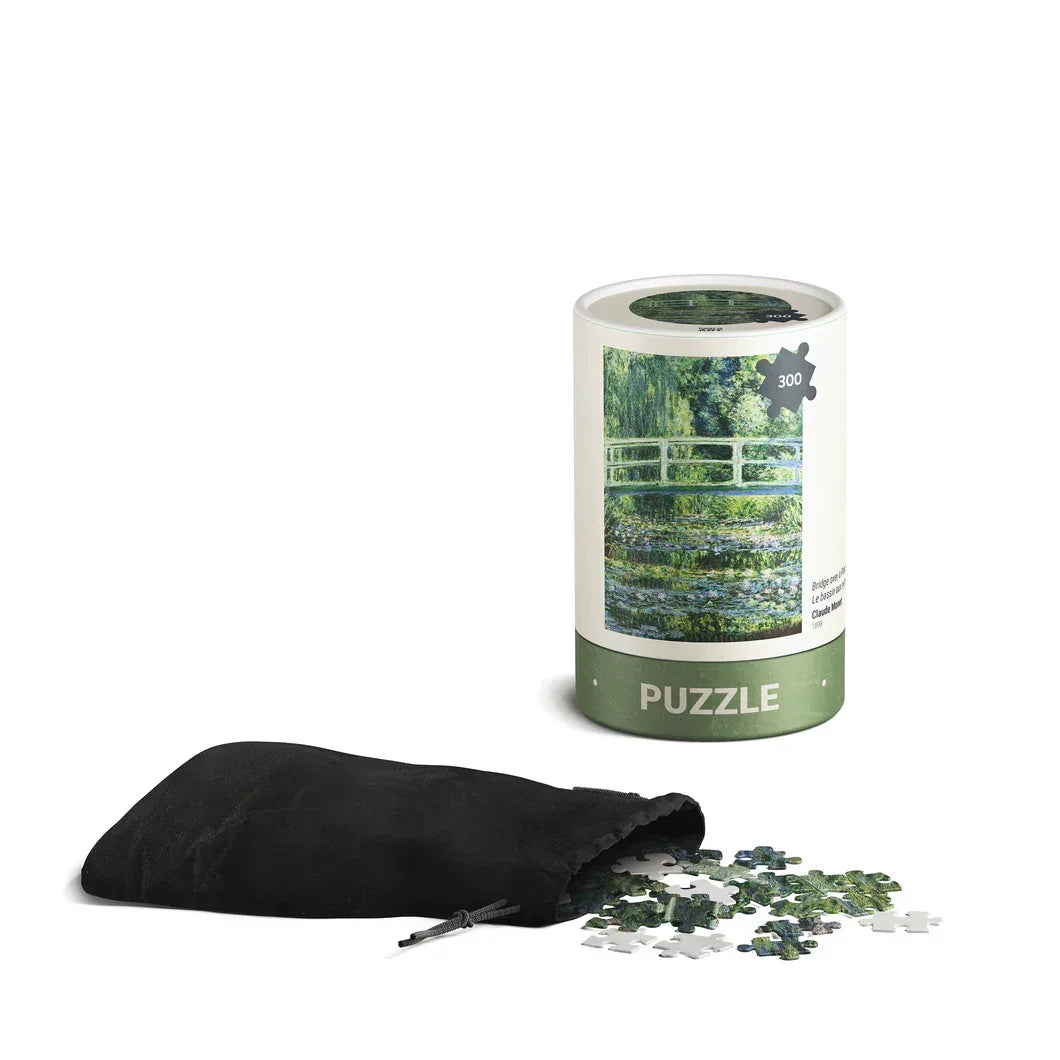 300-piece Monet bridge jigsaw puzzle in a tube, puzzle pieces spilling from black pouch