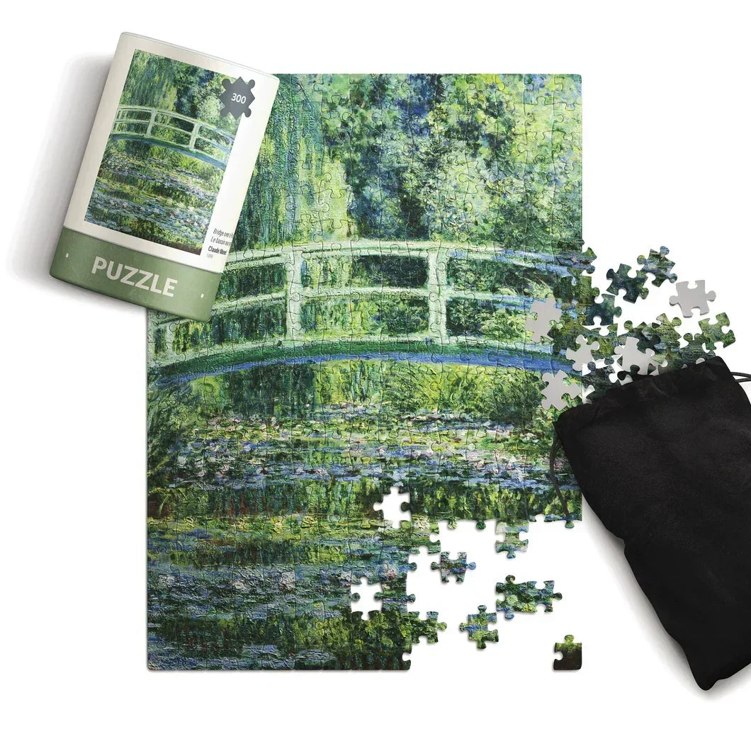 300 piece puzzle featuring a green garden bridge over water with loose pieces and a storage bag