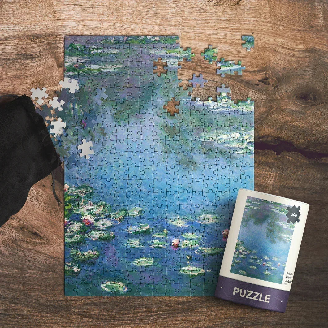 Unfinished 300-piece puzzle with water lilies design on a wooden table, puzzle pieces scattered nearby.