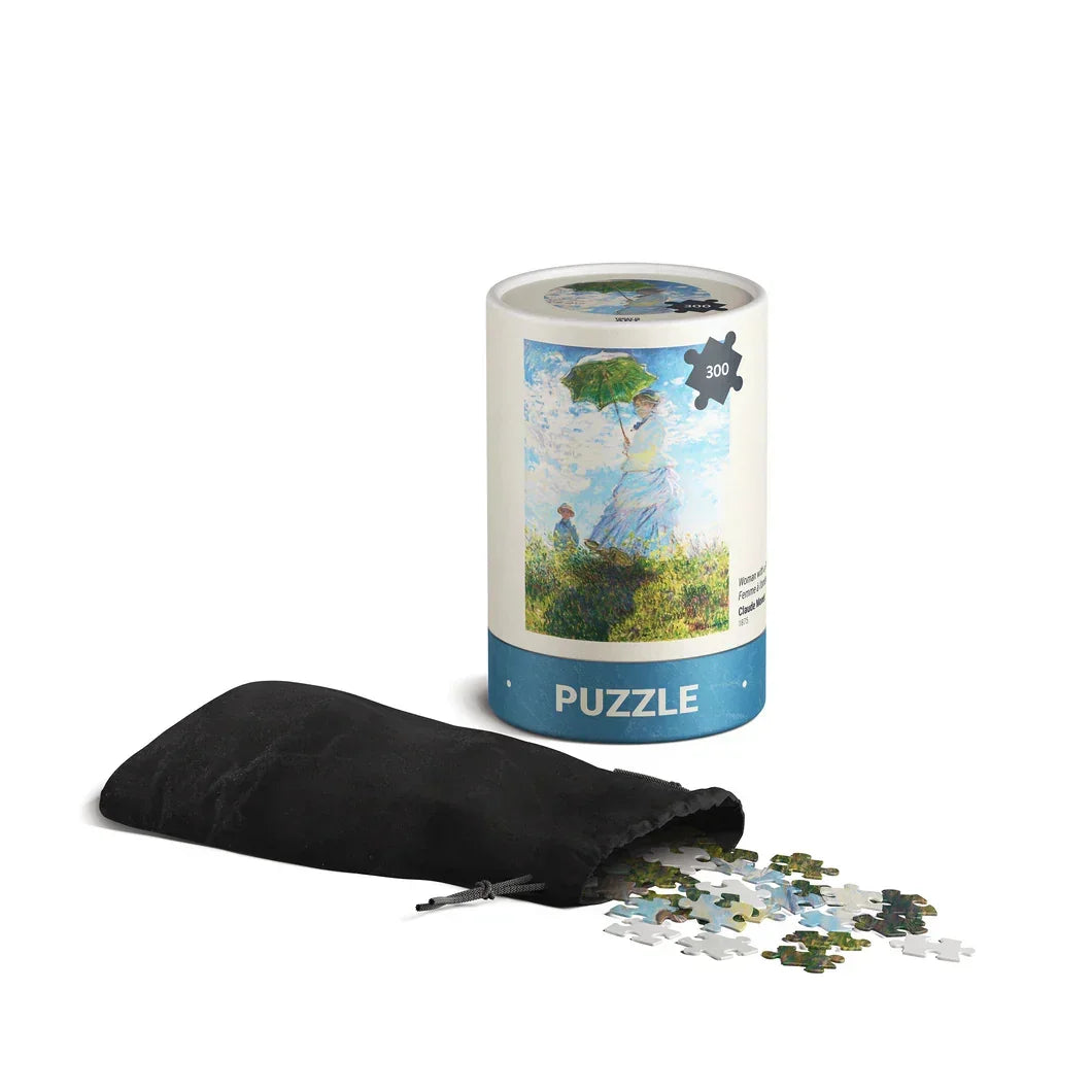 Cylindrical 300-piece puzzle with Monet's Woman with a Parasol art, black pouch with pieces