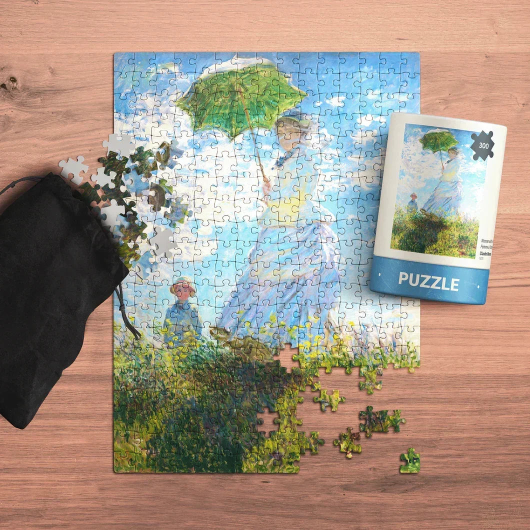 Impressionist art jigsaw puzzle with woman holding green parasol on wooden table