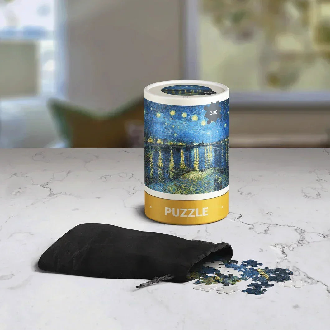 300-piece Van Gogh Starry Night puzzle in cylindrical box with puzzle pieces on marble surface