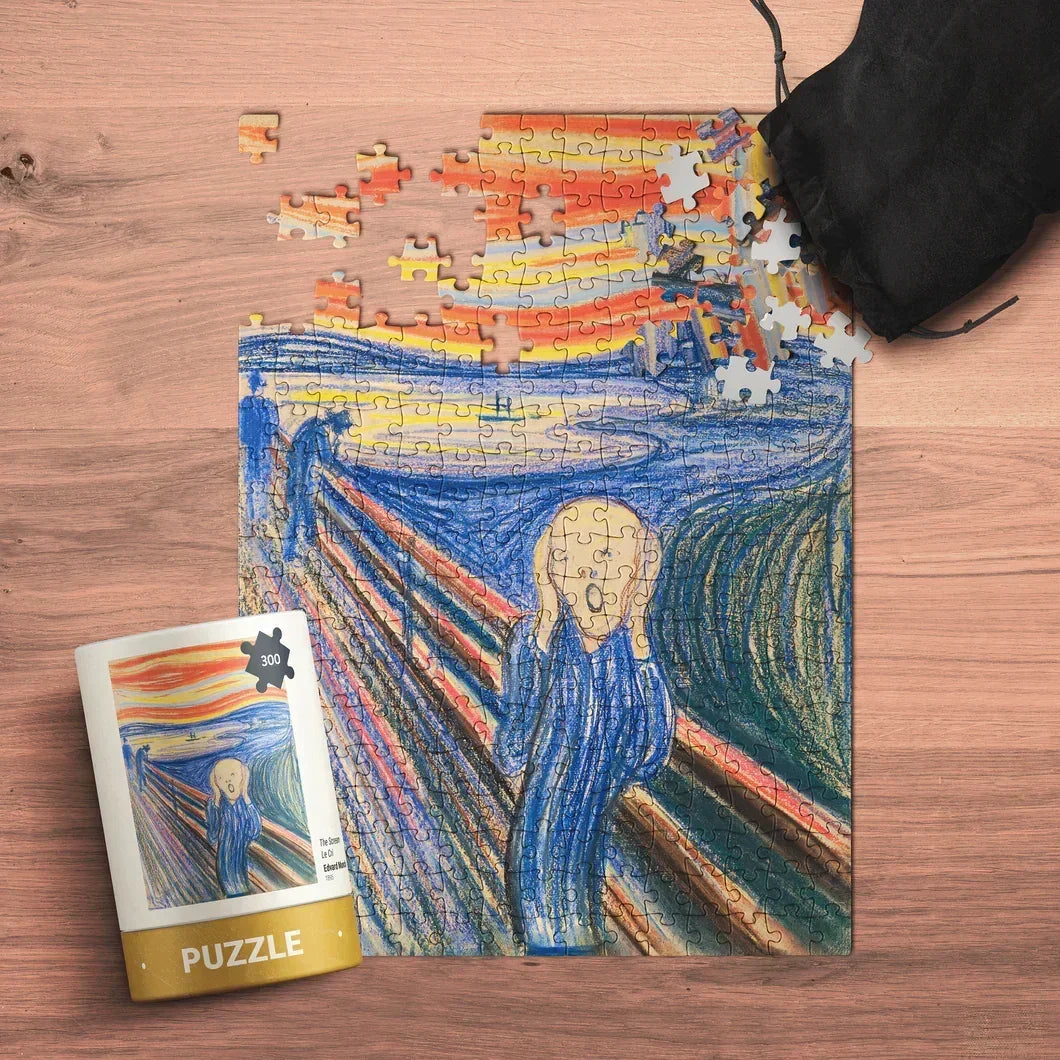 Partially completed The Scream puzzle with pieces, on wood table, puzzle tube nearby
