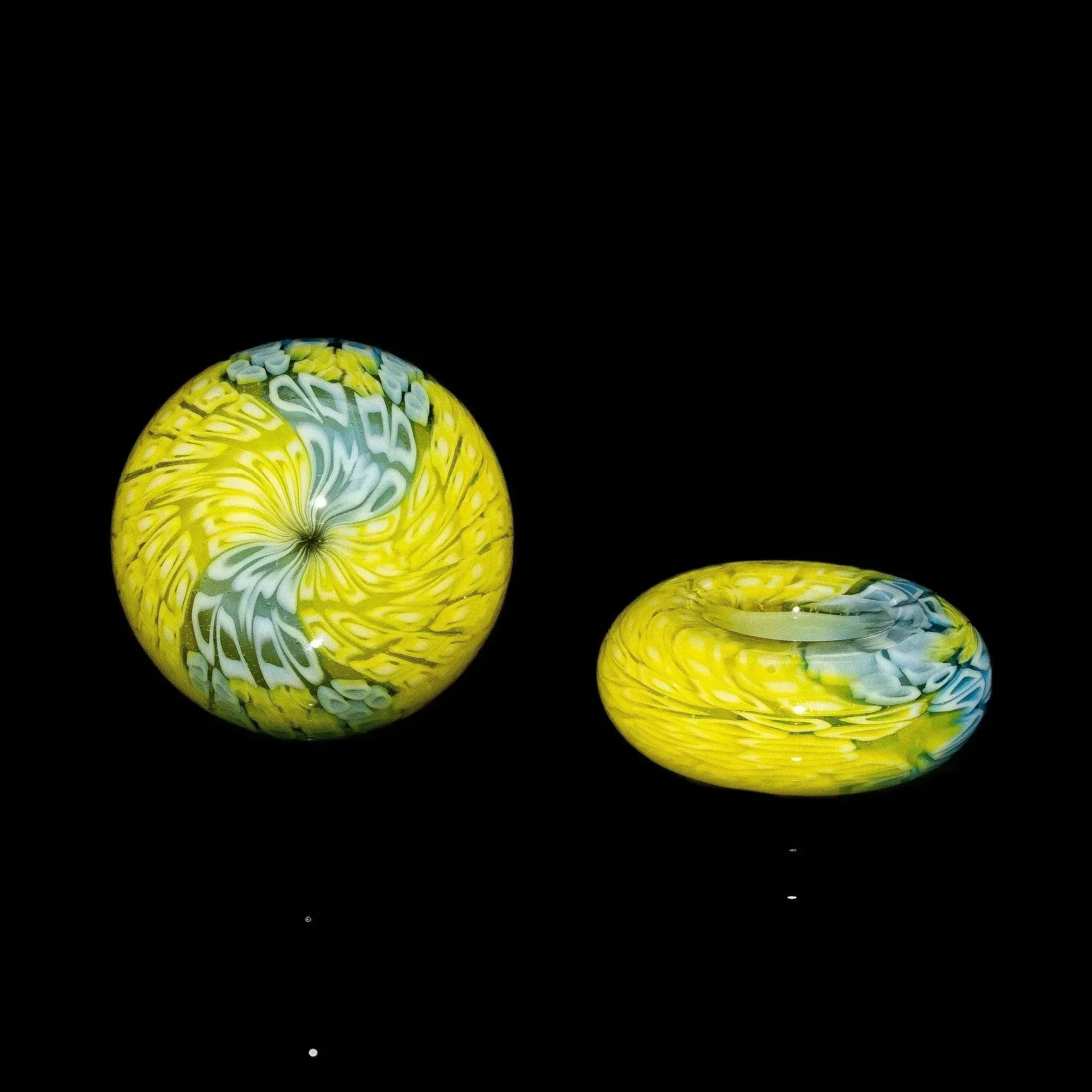 Colorful glass carb caps with yellow, green, and blue swirl patterns on a black background