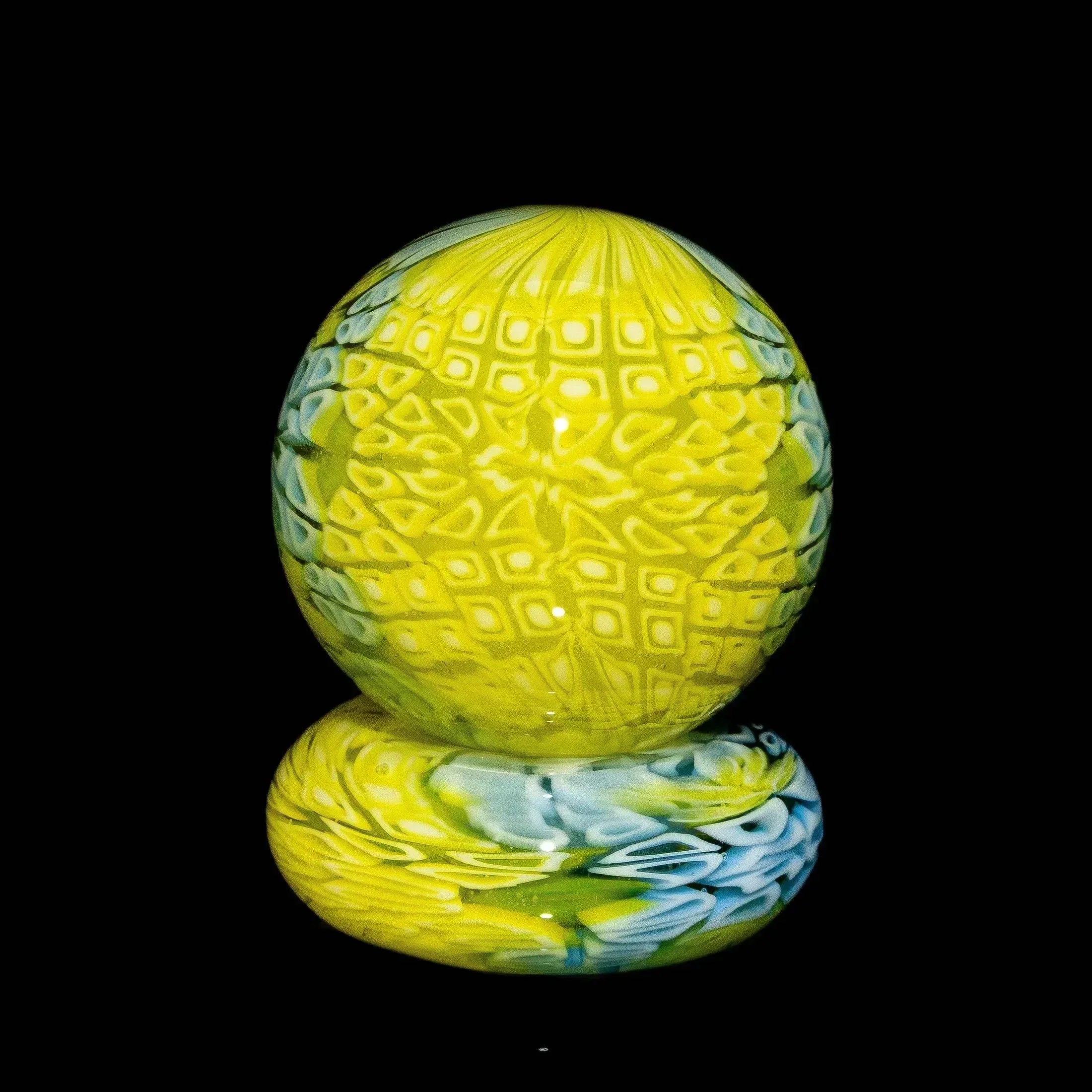 Yellow and blue patterned glass carb cap with diamond texture on black background