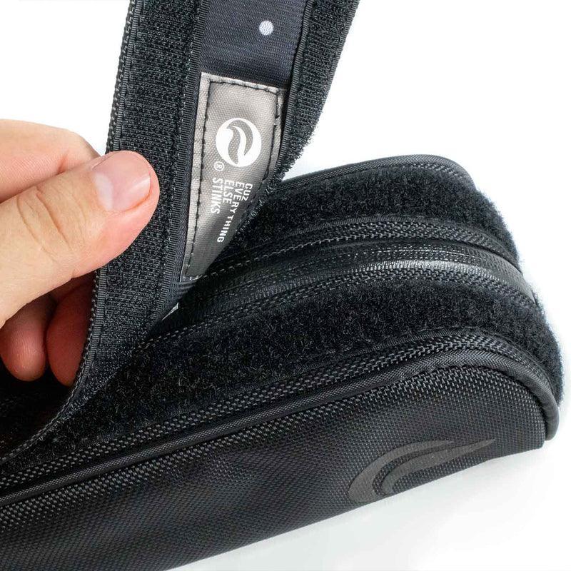 Close-up of a black travel case with zippers and velcro, being opened by hand