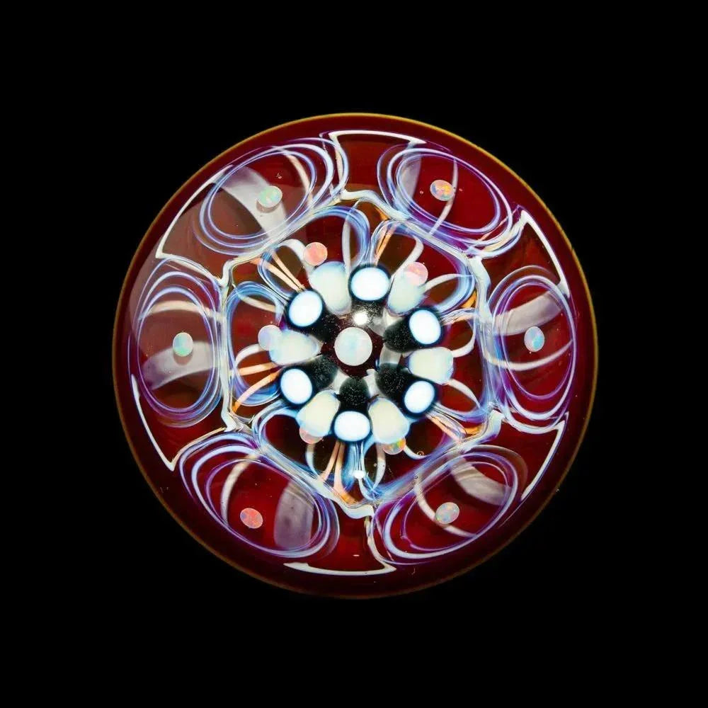 Handcrafted glass marble with opal accents and vibrant swirling patterns on a dark background