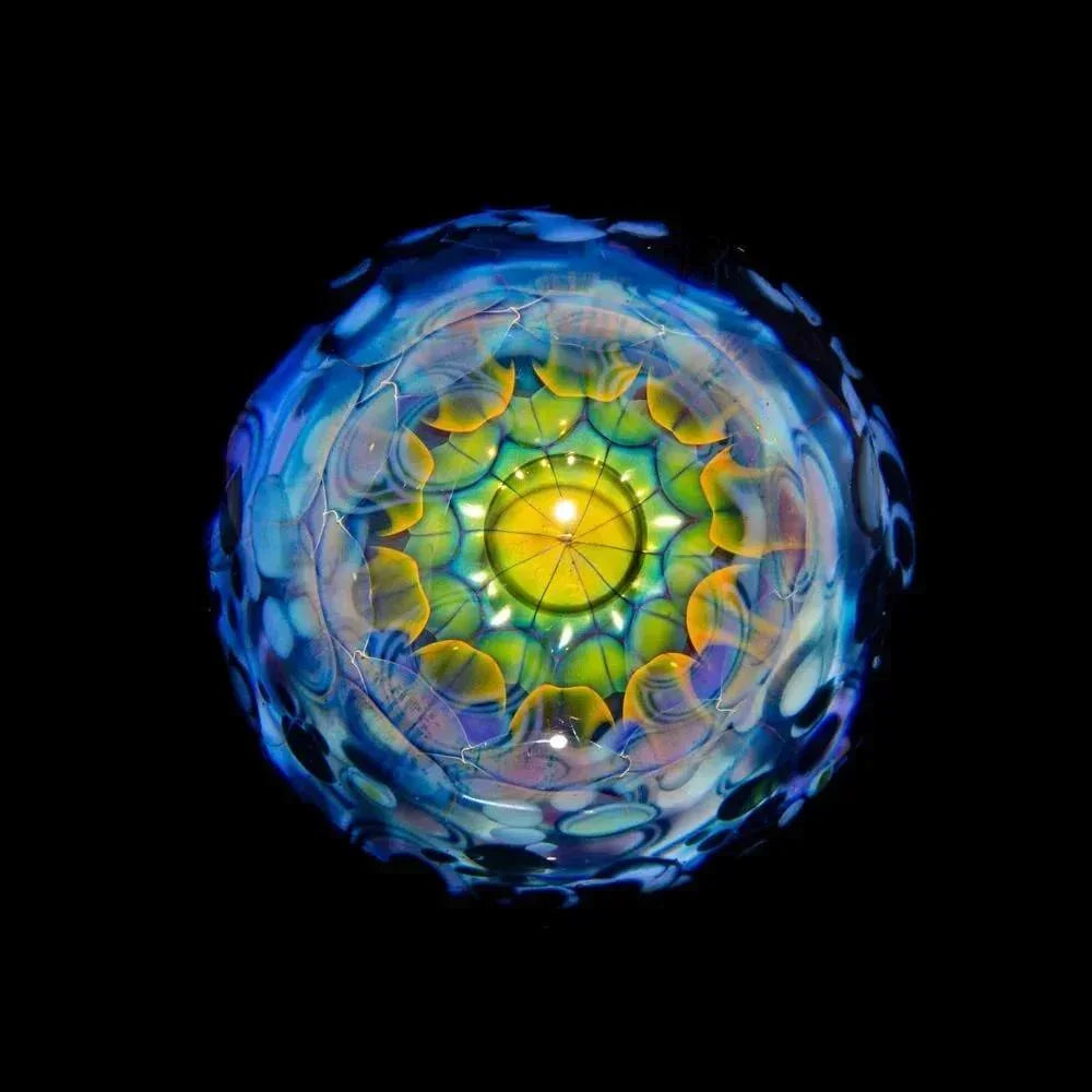 Intricate hand-blown glass art piece with vibrant blue and yellow patterns on black background