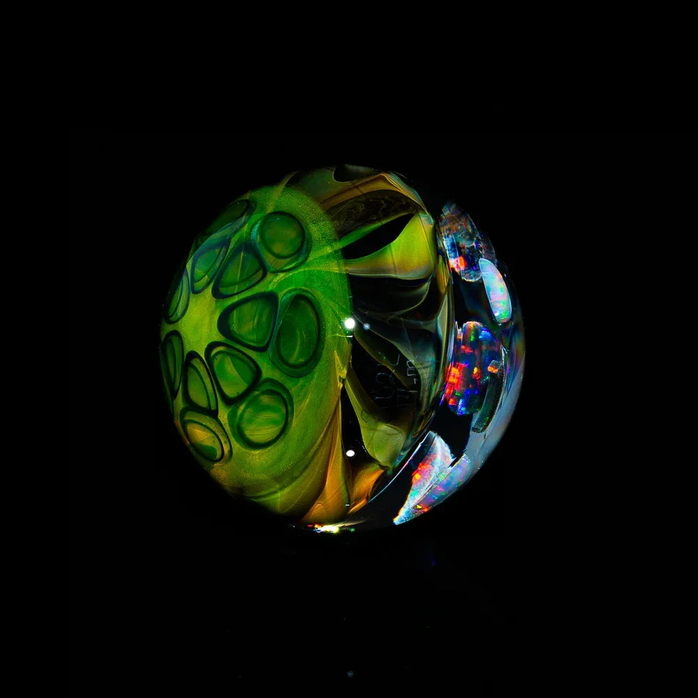 Heady glass marble with green patterns and iridescent details on a black background