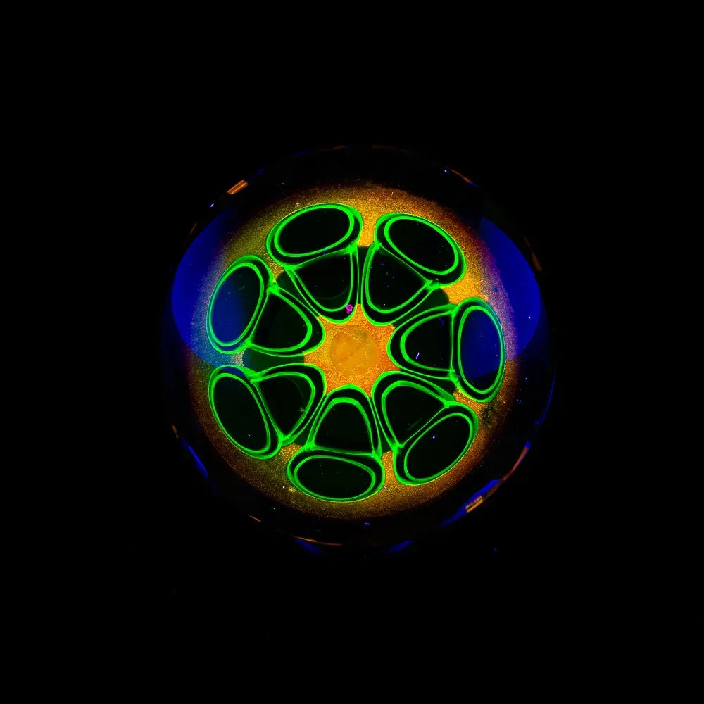 Handcrafted glass marble with glowing neon green and yellow geometric pattern on black background