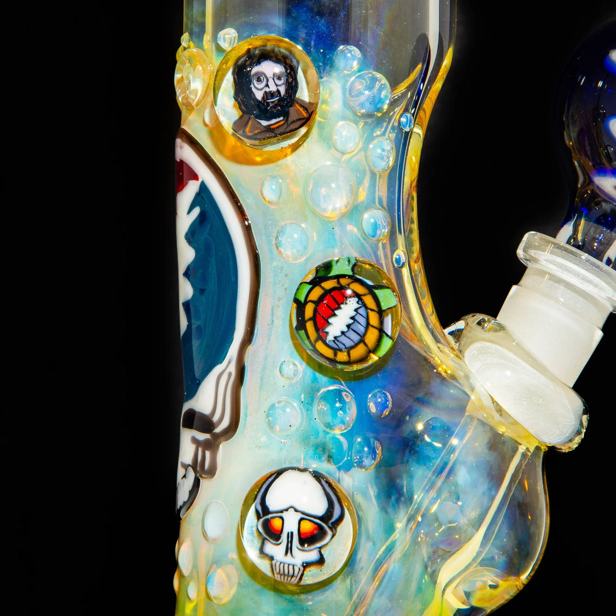 Close-up of a fumed glass bong with colorful marbles featuring skull and face designs