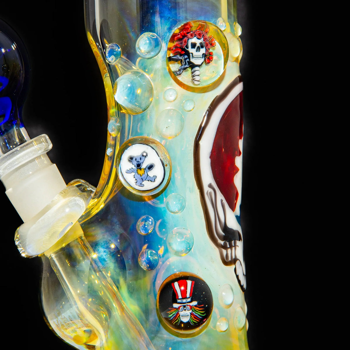 Close-up of a fumed glass bong with colorful decorative marbles and intricate artwork
