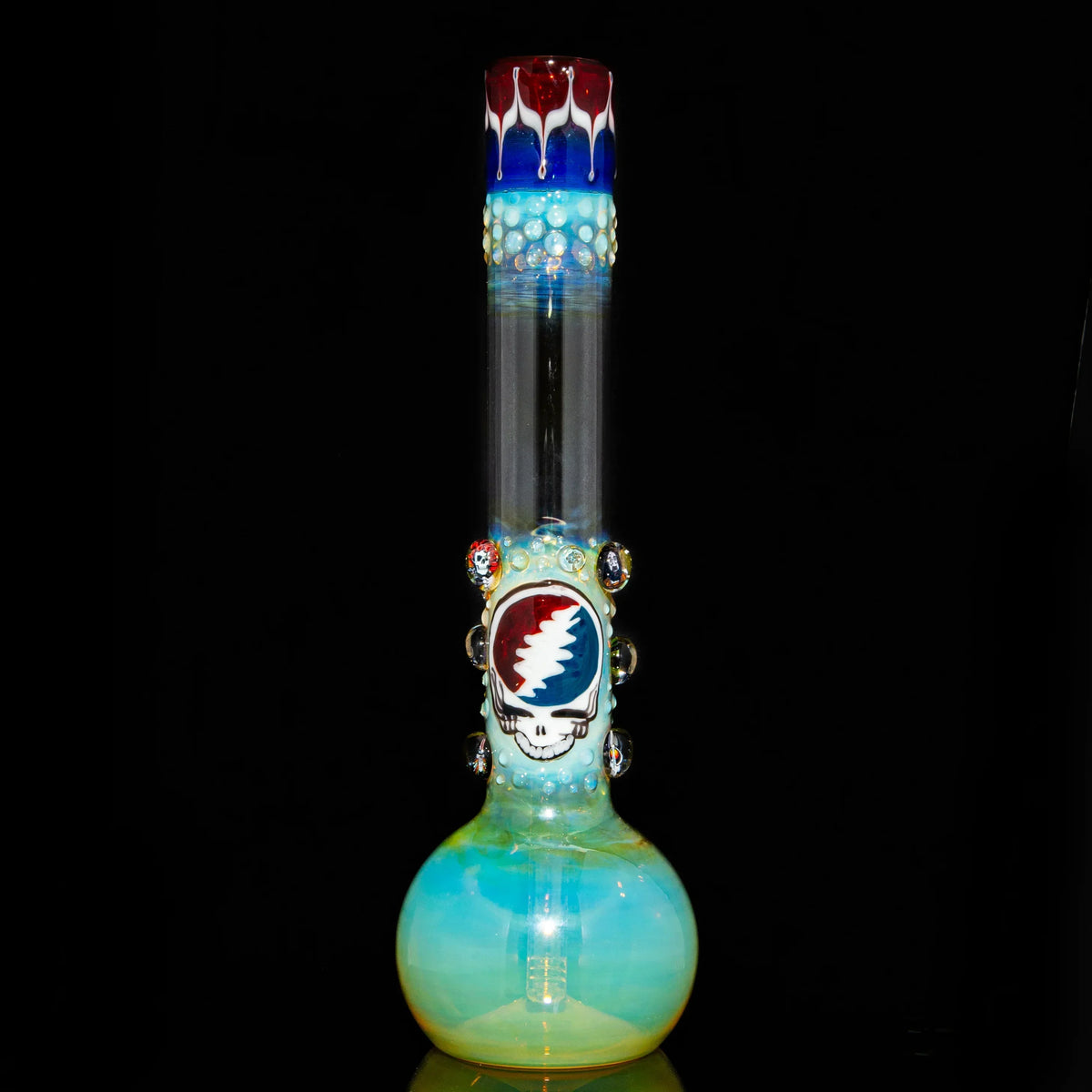 Heady glass bong with colorful fumed accents and skull art on a black background