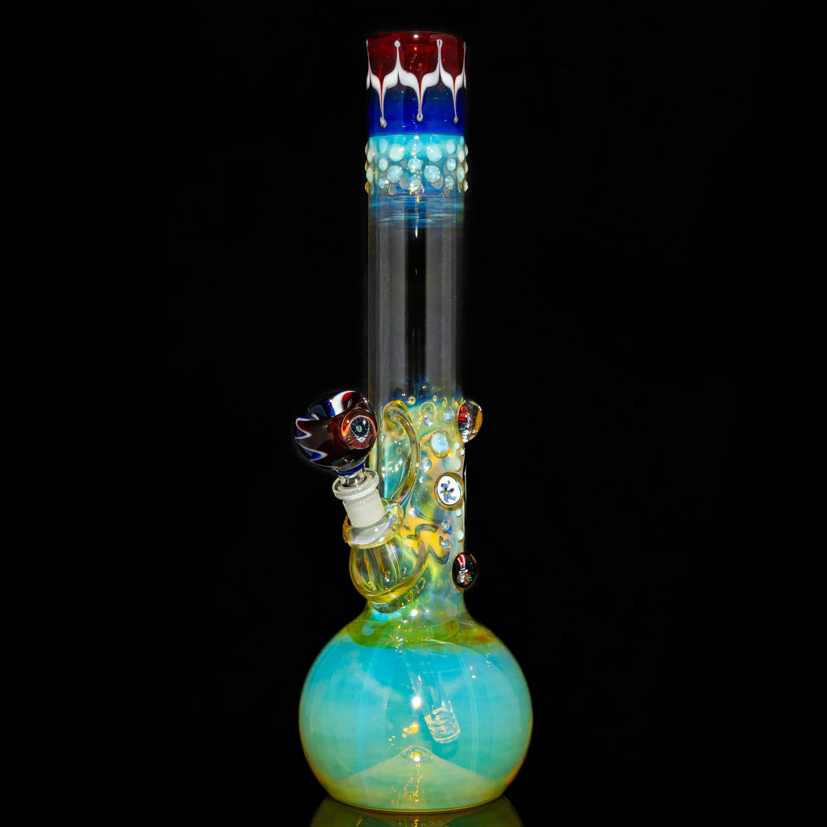 Colorful glass water pipe with fumed design, decorative marbles, and patterned bowl on black background.