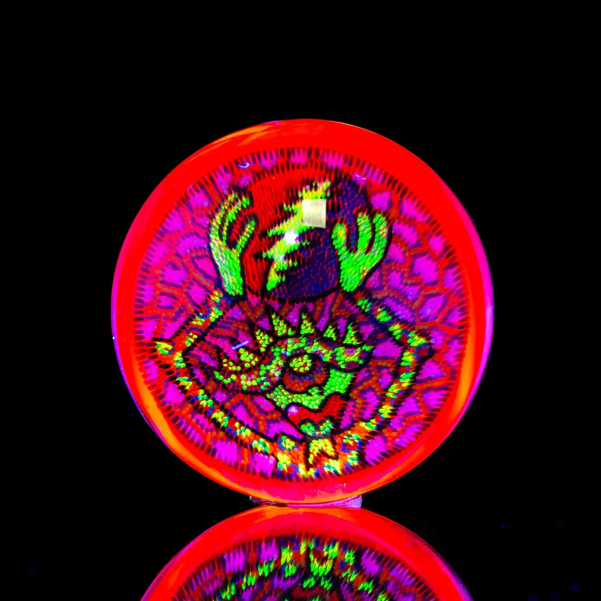 UV reactive glass art disc with vibrant neon crab design on black background