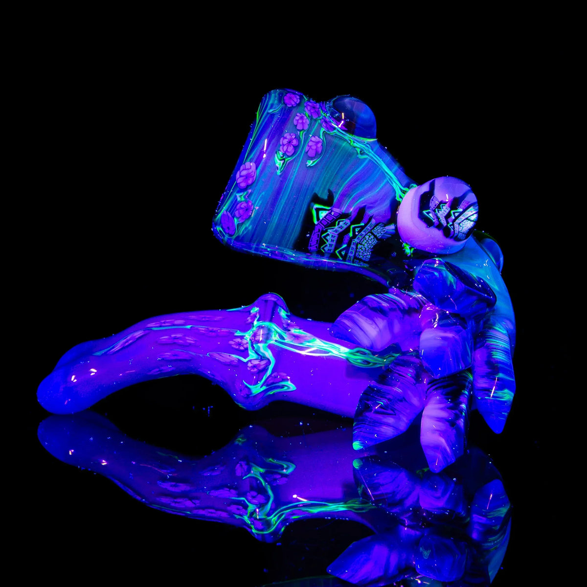 Colorful UV-reactive glass pipe with intricate floral and abstract designs glowing in blacklight