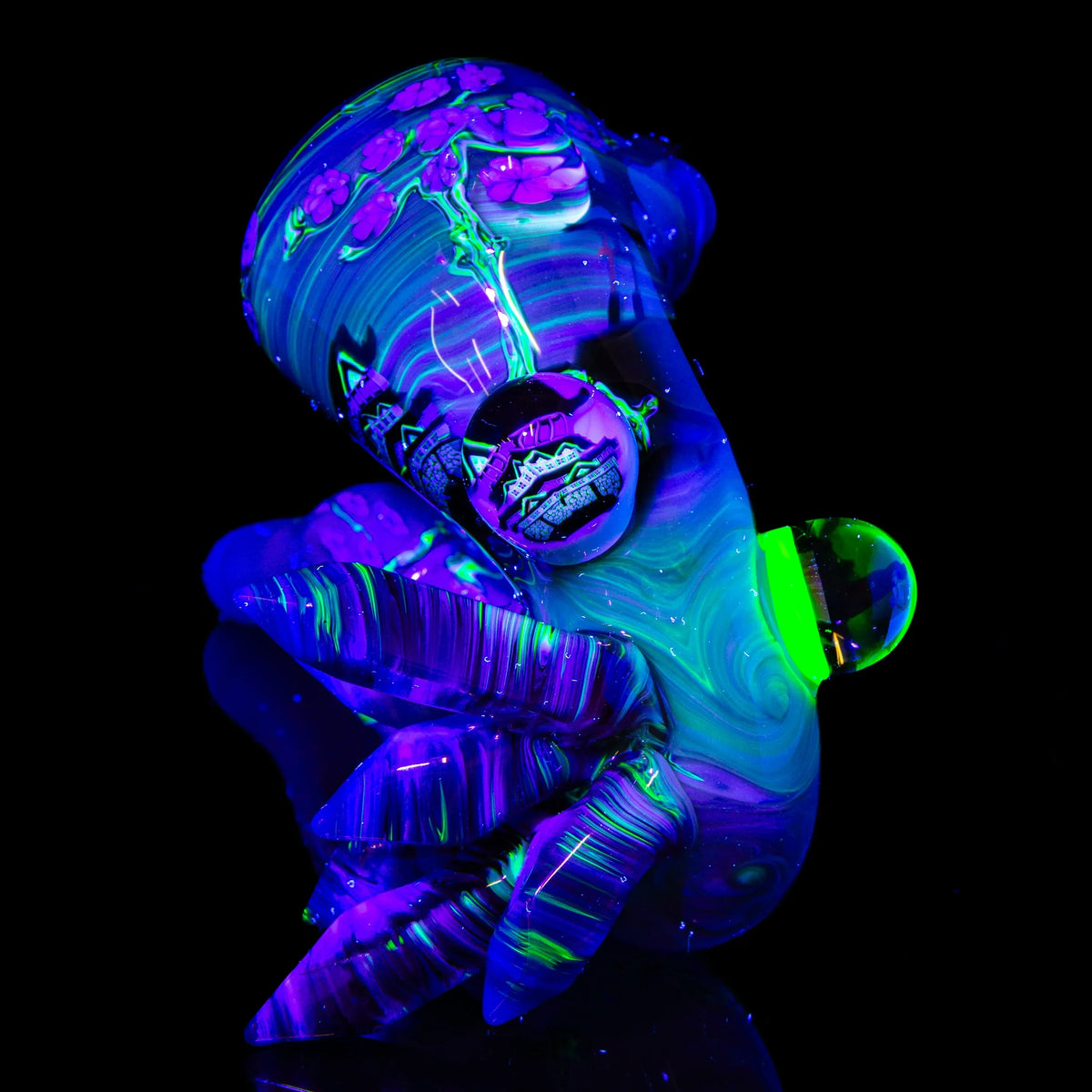 UV-reactive heady glass pipe with vibrant neon swirls, floral accents, and marble details