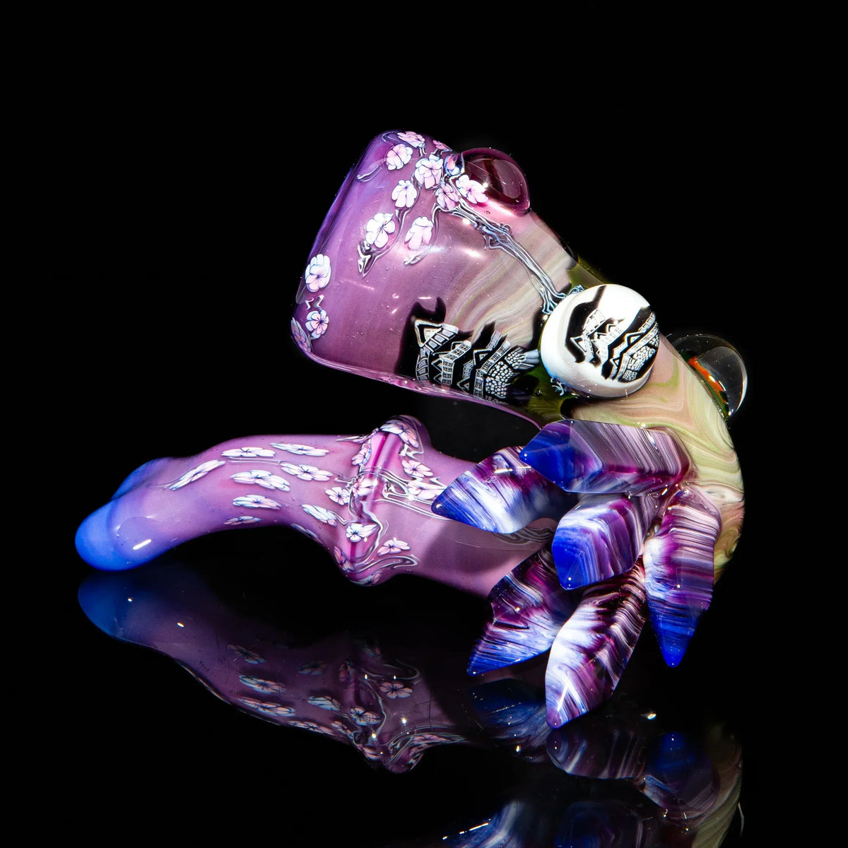 Purple and pink heady glass pipe with floral designs and sculpted leaf accents on black background