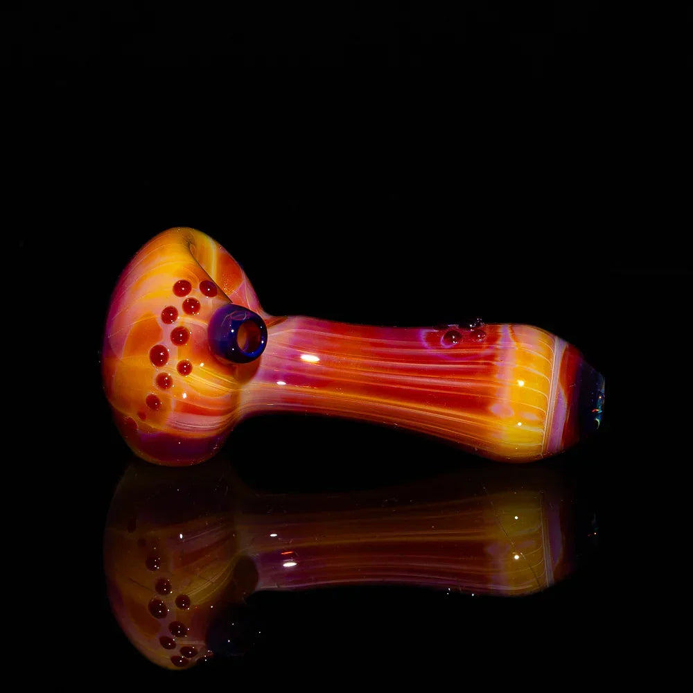 Colorful glass spoon pipe with red and orange swirls, displayed on a black background.