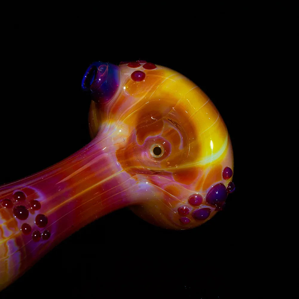 Colorful handblown glass pipe with vibrant yellow, orange, and purple accents on black background