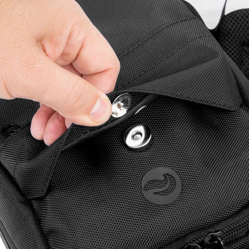 Hand unbuttoning a black smell-proof backpack pocket with textured fabric