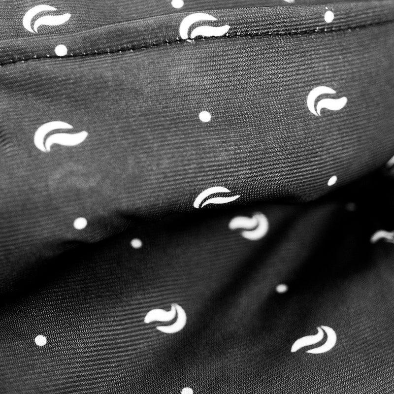 Closeup of black fabric with white crescent and dot pattern, soft textile texture