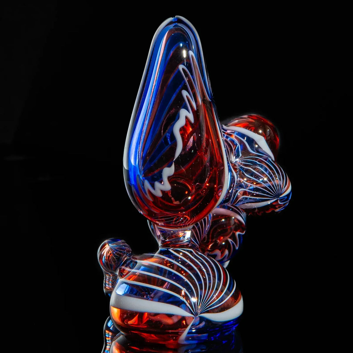 Red, blue, and white heady glass hand pipe with intricate swirled patterns on black background