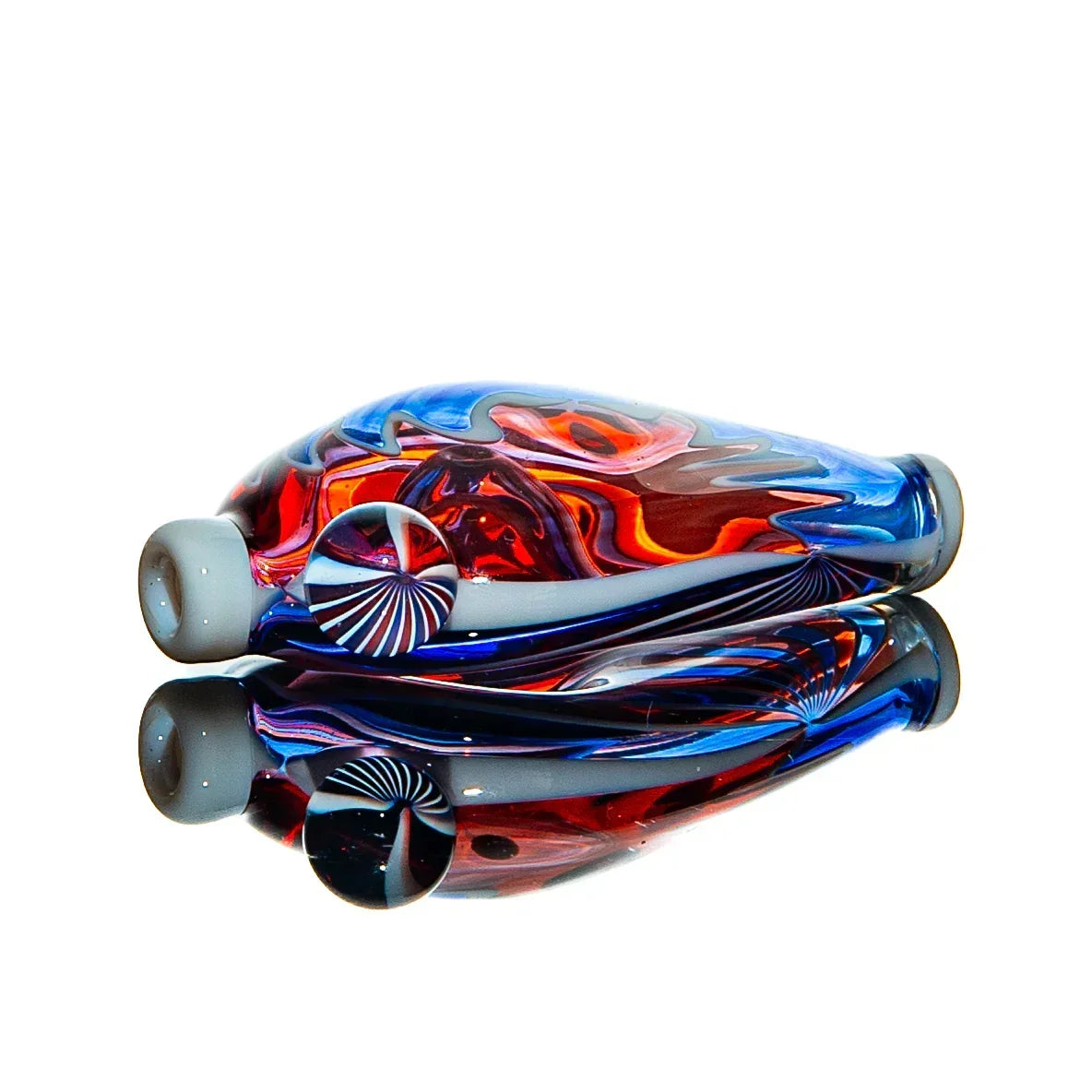 Hand-blown glass chillum with vibrant red and blue colors, mirrored on a reflective surface.