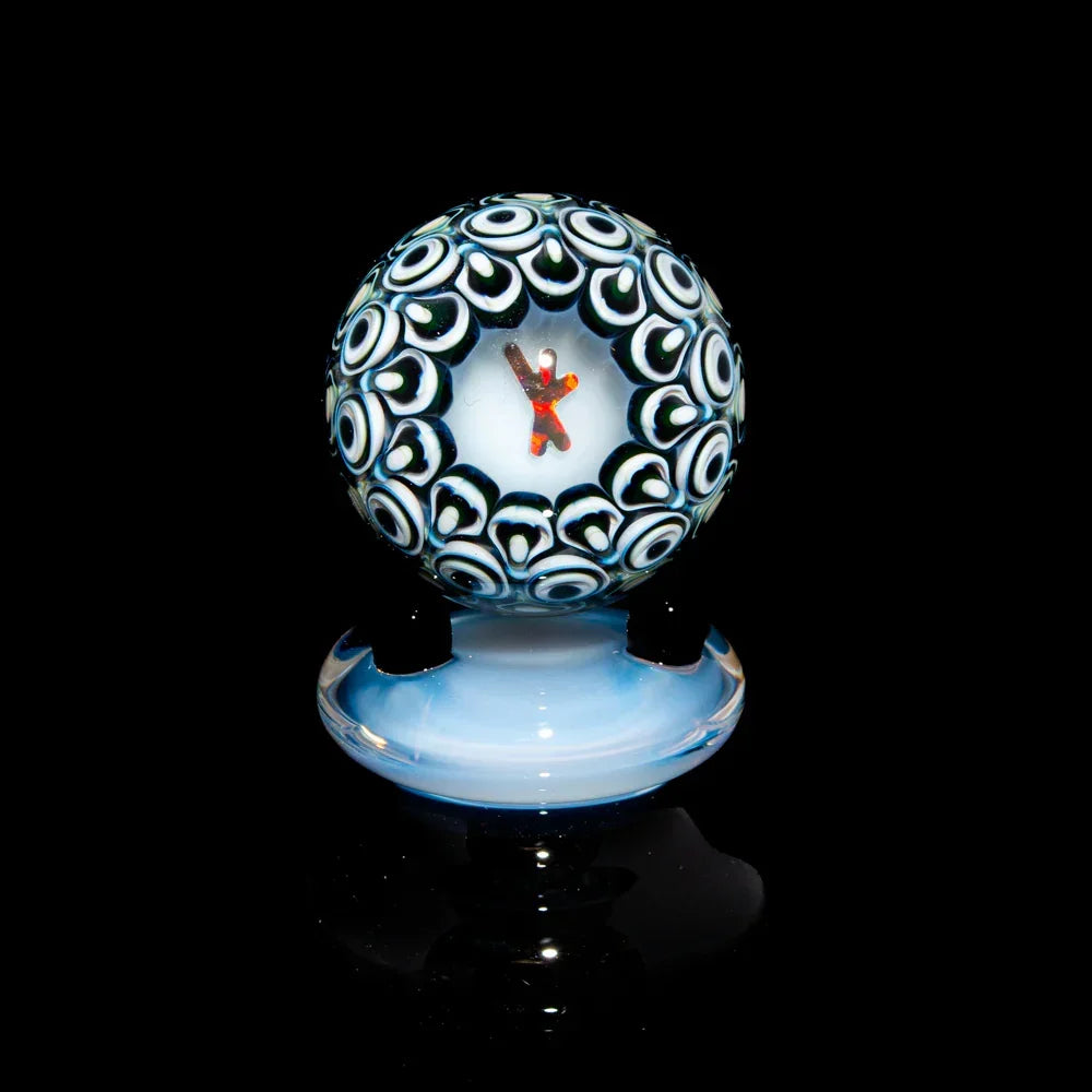 Intricate glass marble with blue and white patterns on display stand, black background