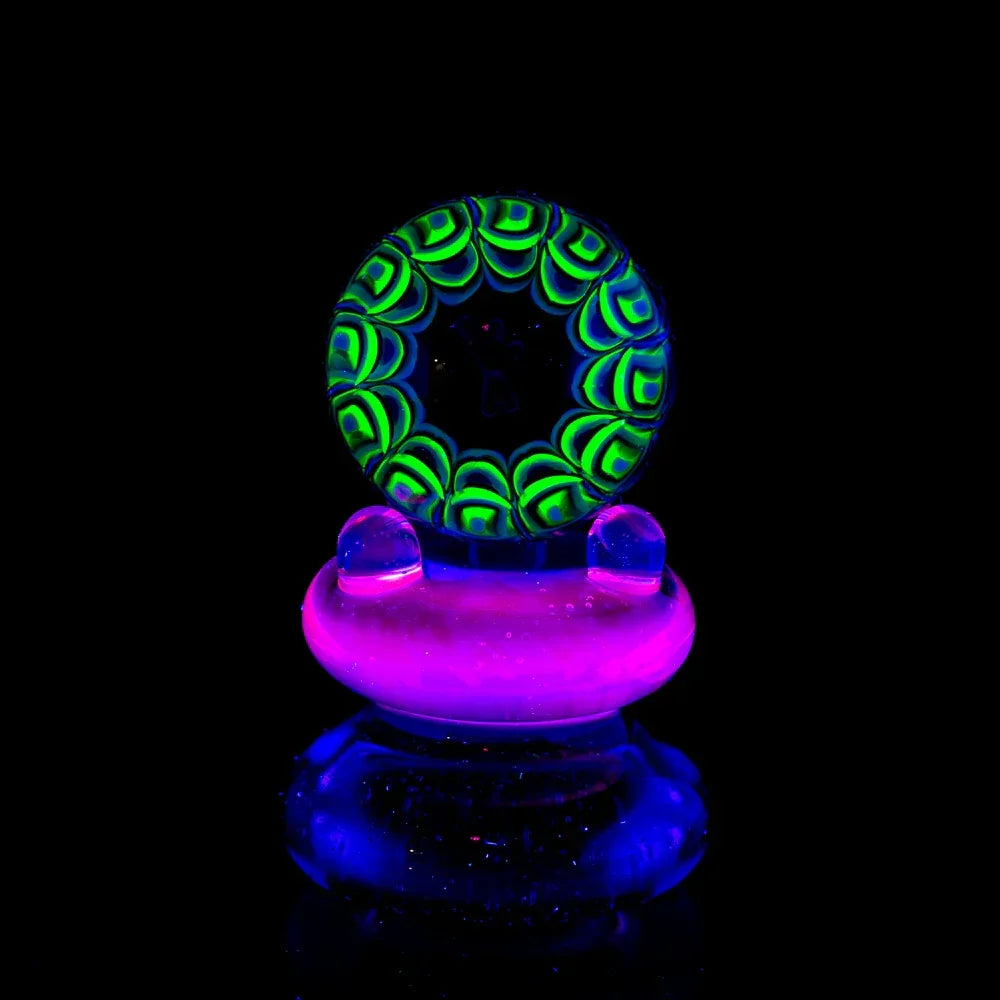 UV-reactive glass marble with green and blue psychedelic design on black background